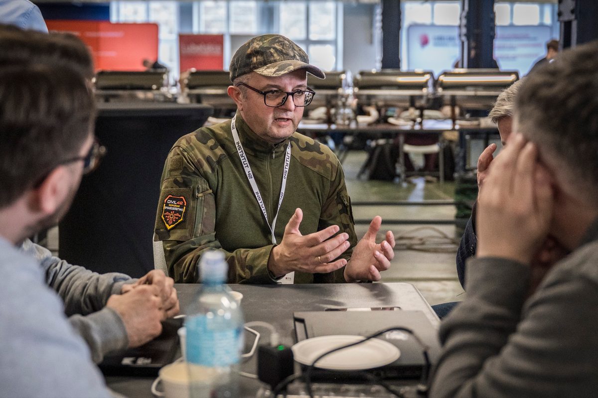 Mentor rozmawia z uczestnikami hackathonu CIVIL42 przy wspólnym stole